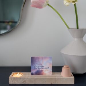 Houten plankje met daarin een waxinelichtje en een klein urntje. In het midden van het plankje is er ruimte voor een foto of een kaartje.