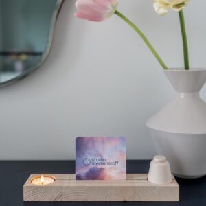 Houten plankje met daarin een waxinelichtje en een klein urntje. In het midden van het plankje is er ruimte voor een foto of een kaartje.